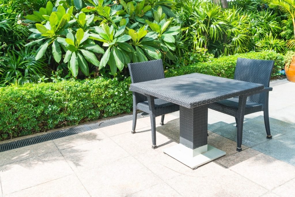 Backyard concrete patio with outdoor table and chairs.