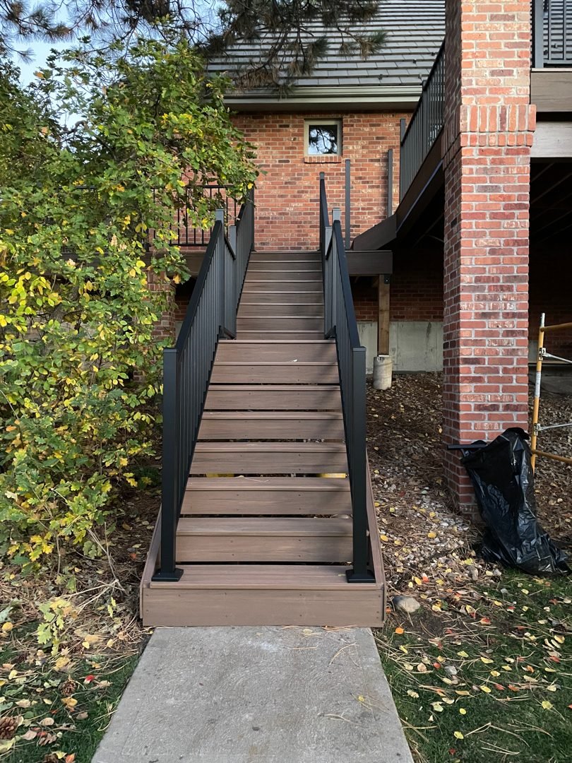 Composite deck stairs with Deckorators black aluminum stair railing built by Elevate Landscape & Spas