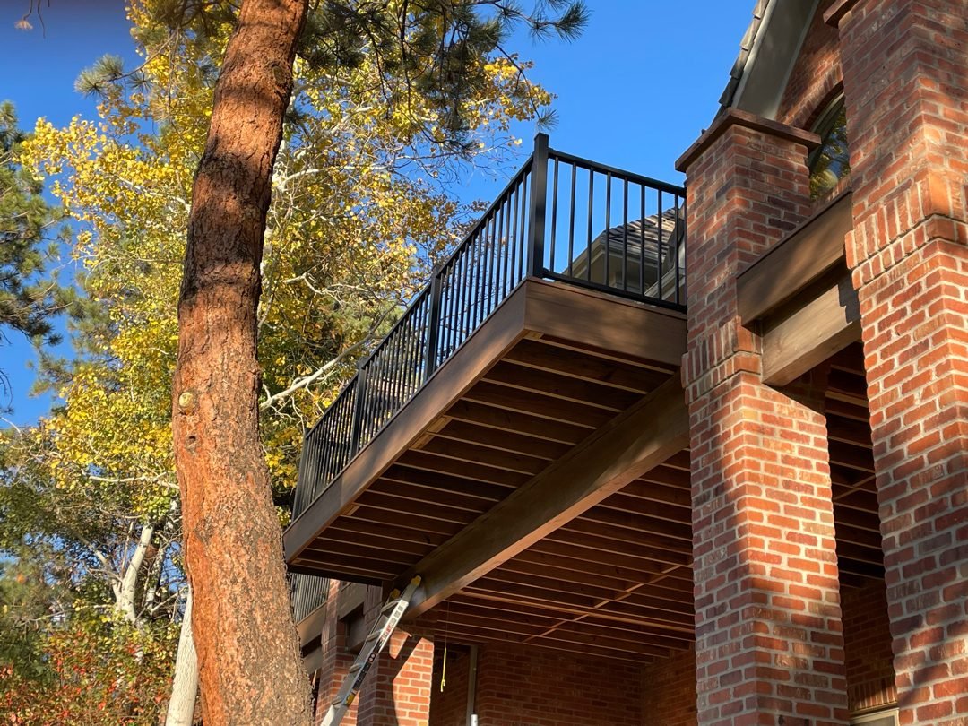 Second-story composite deck with Deckorators black aluminum railing on a brick home in Castle Rock