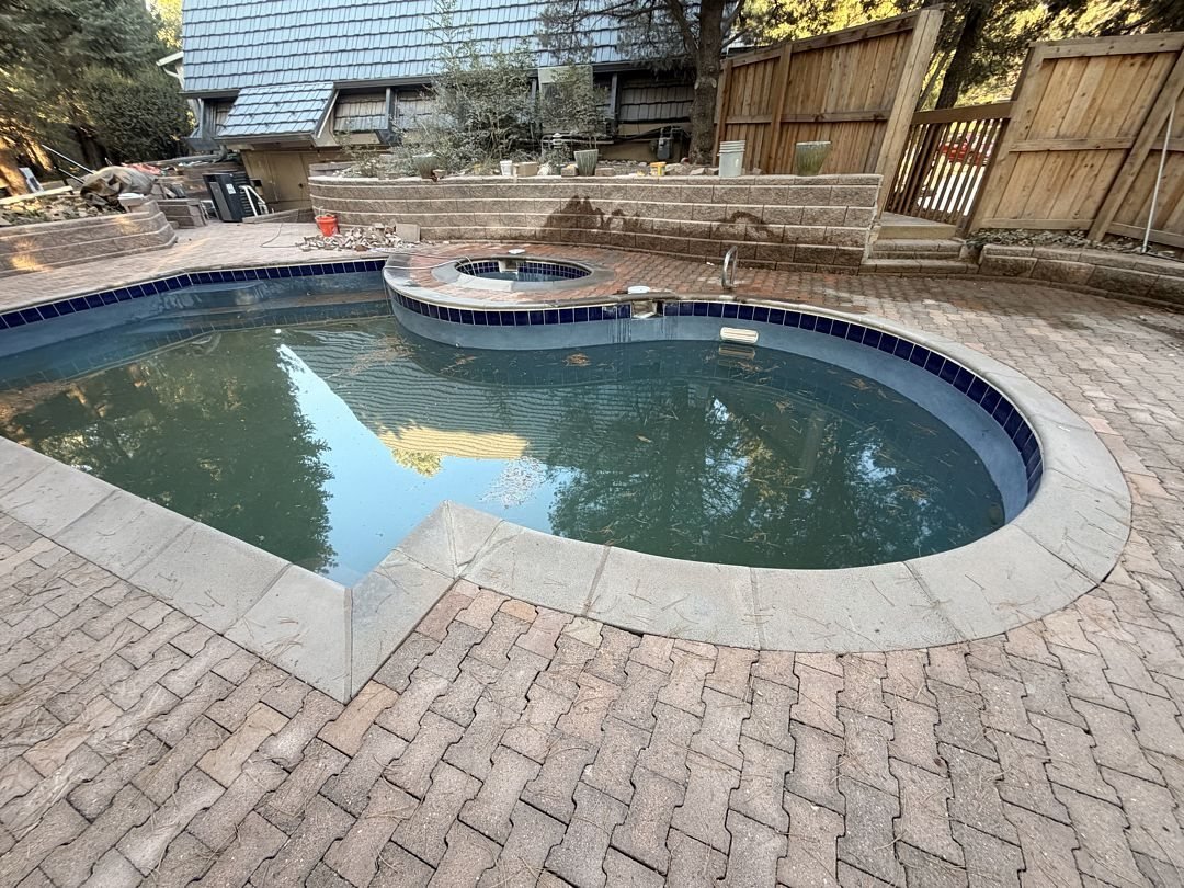 Pool deck resurfacing: herringbone pavers reset around a pool and spa with stone coping