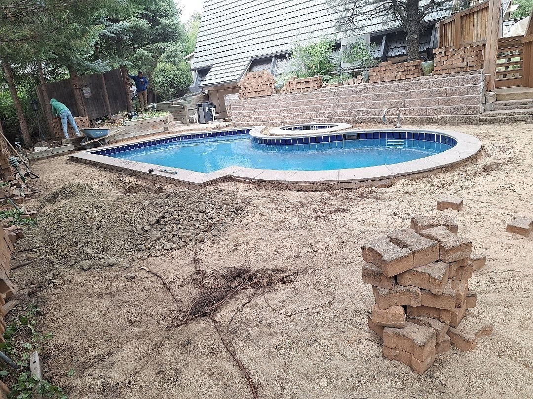 Pool deck pavers lifted and stacked while the base and plumbing are repaired